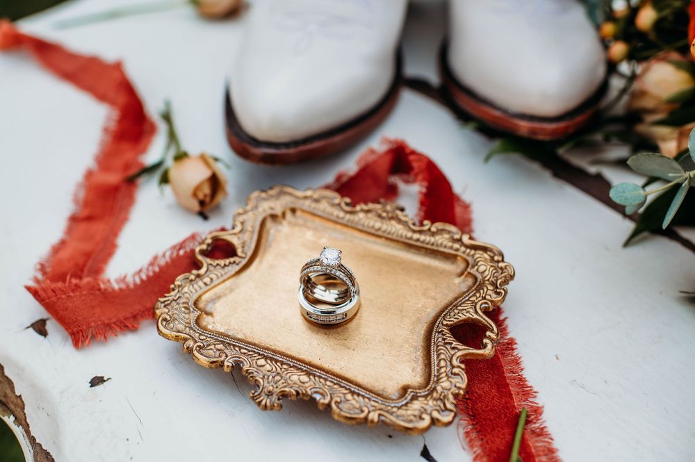 Ornate gold trays and decorative items arranged with red ribbons and holiday decor on white surface.