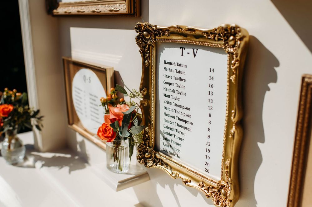 Ornate gold picture frames hang on a white wall with text displays in a gallery or museum setting.