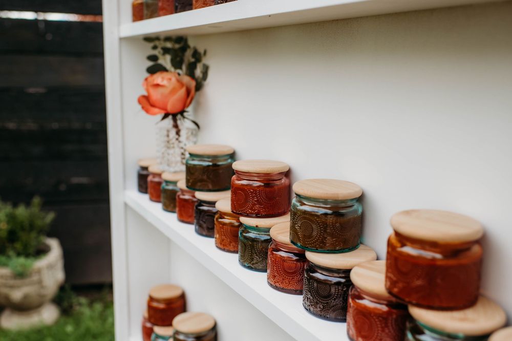 Glass jars filled with homemade preserves and canned goods lined up neatly on white shelving.
