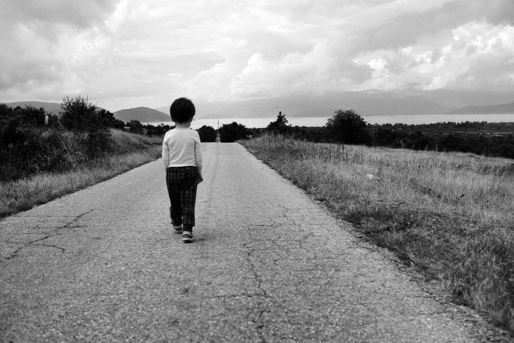 A child walking on an empty road in Prespa, North Macedonia.