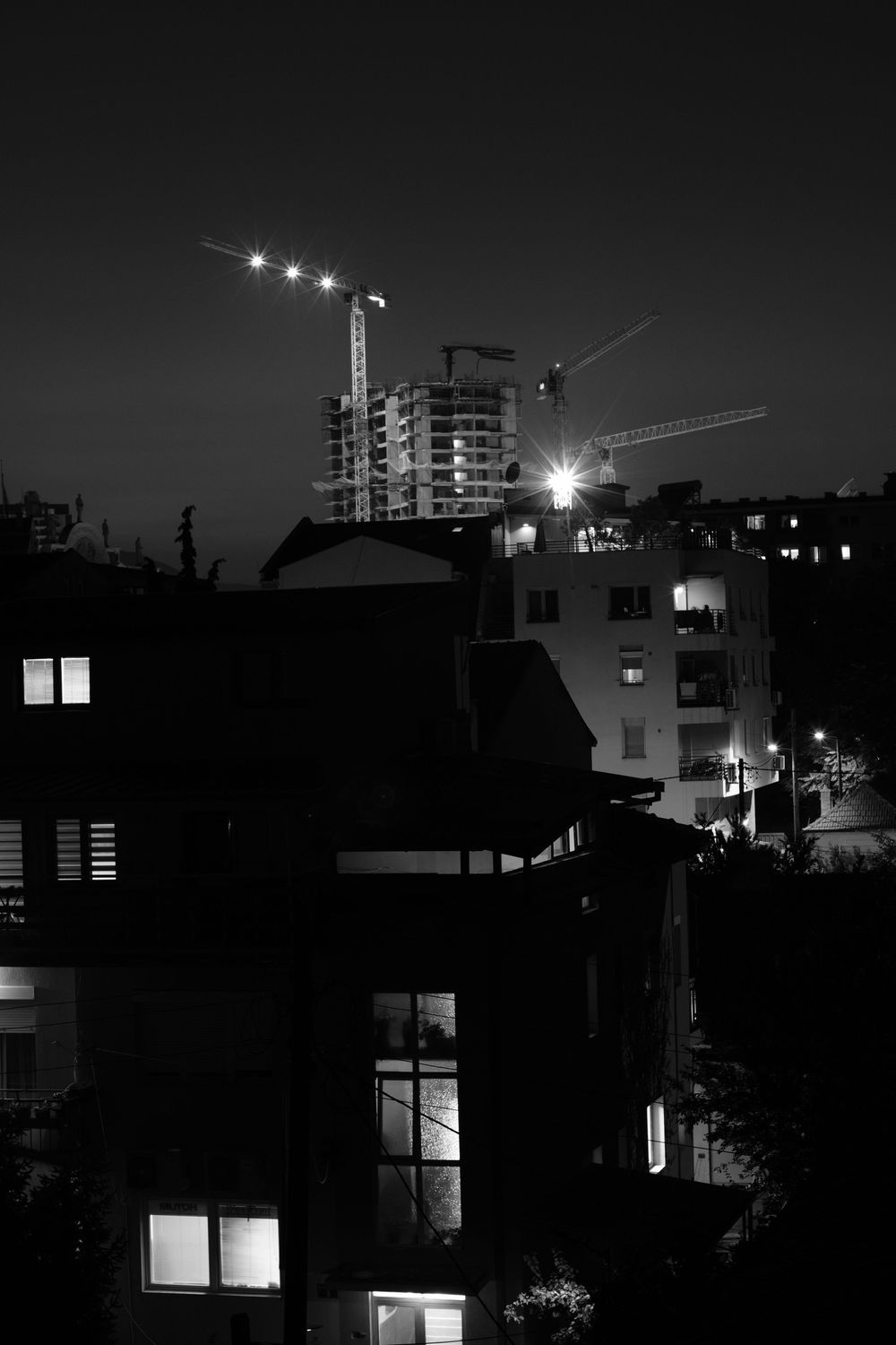 Construction in Skopje, North Macedonia during the night with window lights in the foreground.