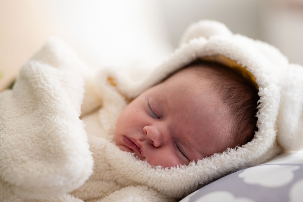 Sleeping newborn snuggled in a soft white blanket during a studio session in Mountain Home, Arkansas