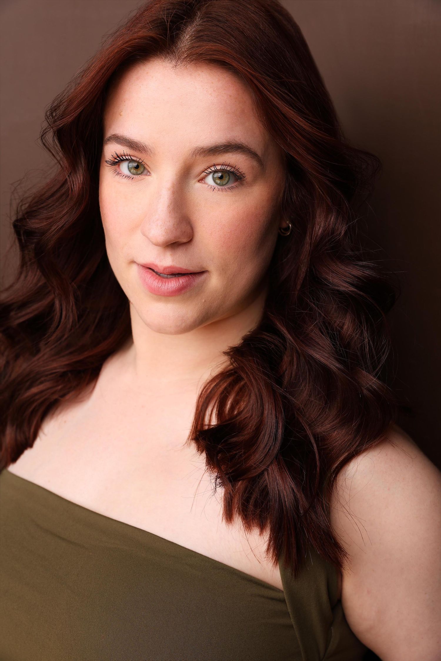Professional headshot of a business woman wearing a striped shirt and gray blazer against an orange background.
