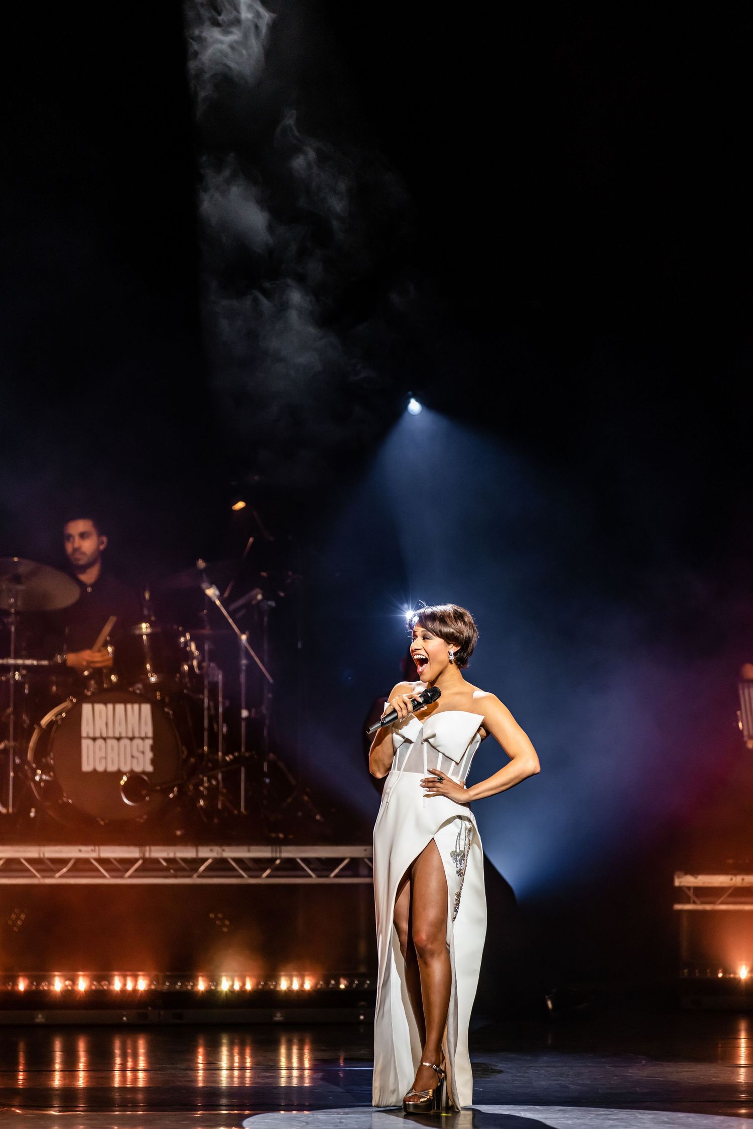 Dramatic solo performance on stage with atmospheric lighting and smoke effects.