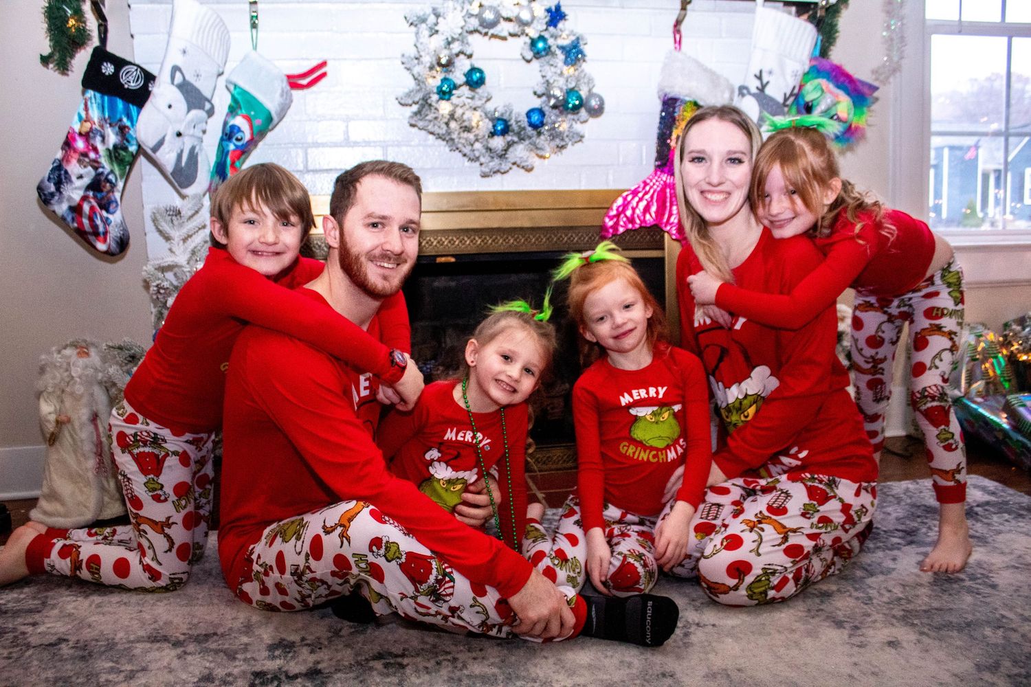 Family in matching pajamas posing together in front of a  fireplace during a holiday photo session with a Chattanooga photographer