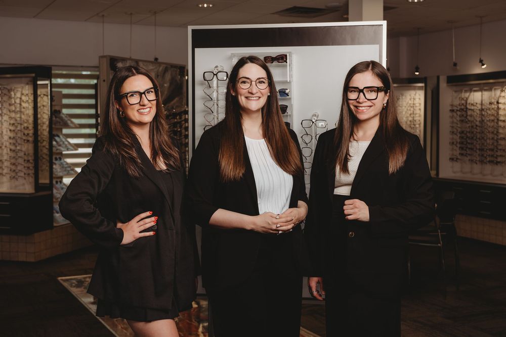 Group of professionals in business attire pose together in an office setting with dark interior decor.