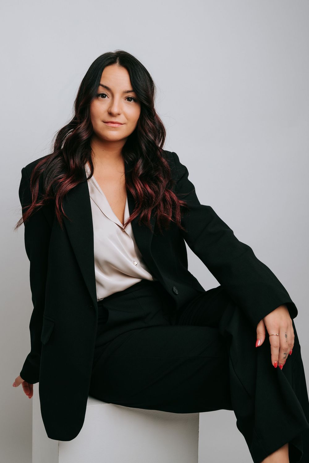 Professional studio portraits showing a person in a black blazer and white blouse posing against a light gray background.