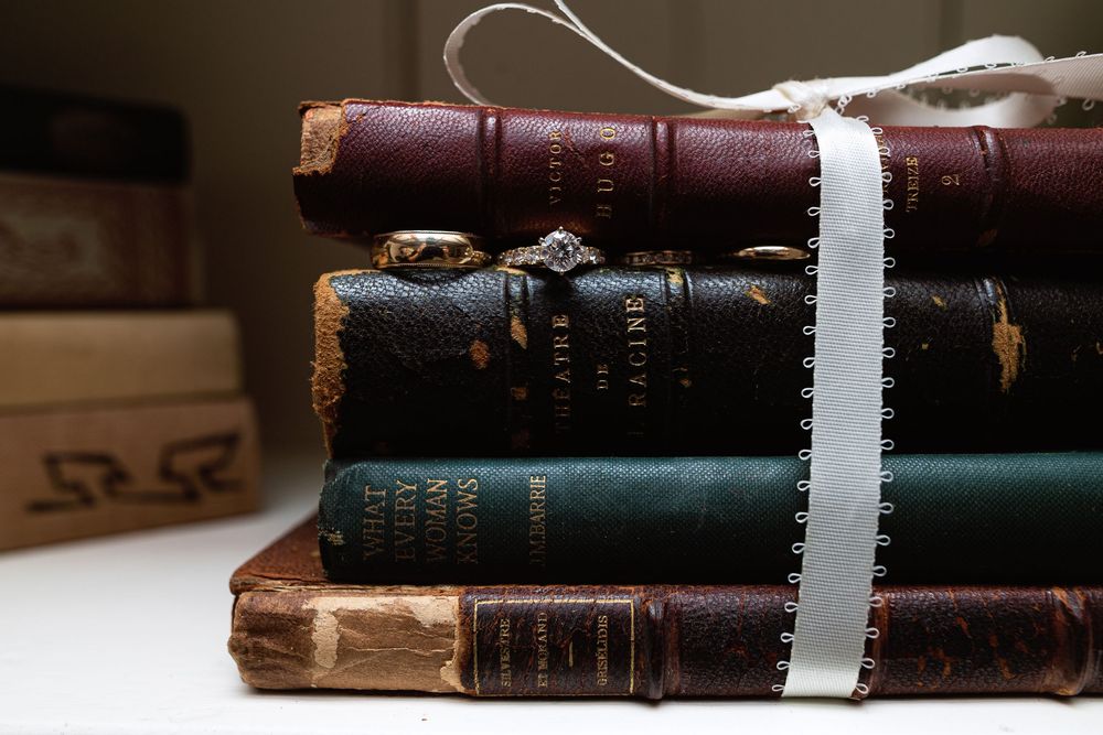 A stack of vintage leather-bound books with worn covers tied together with white ribbon.