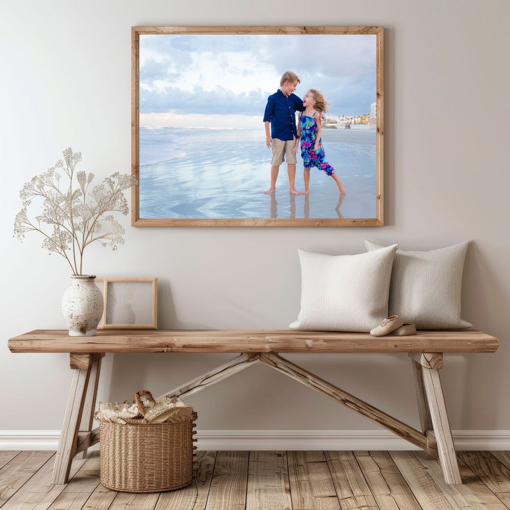 Coastal scene photograph displayed above wooden bench with white cushions and natural decor.