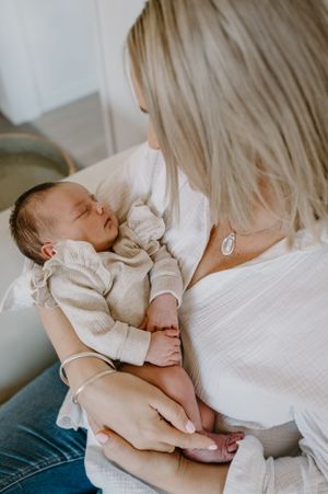 A peaceful moment between caregiver and sleeping infant dressed in white.