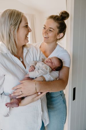 A joyful moment shared while holding a newborn baby in a bright, white room.