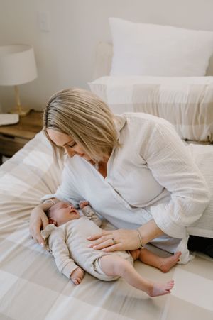 A tender moment on white bedding as an infant rests peacefully.