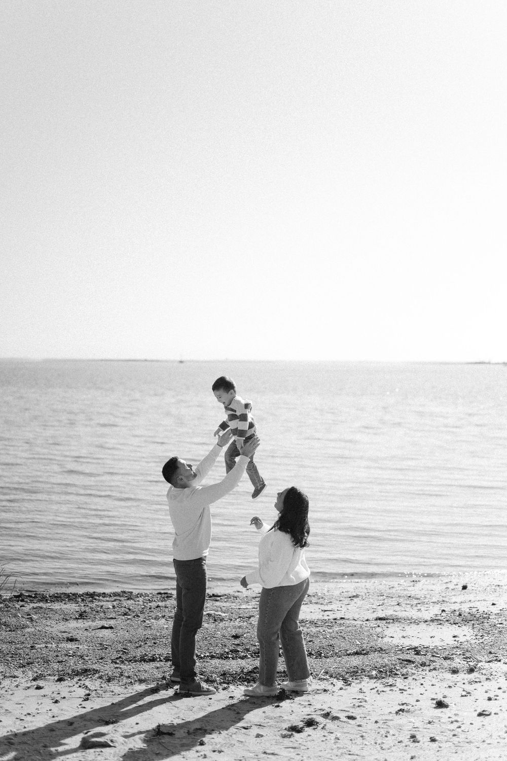 A couple dances together on a beach at sunset in a romantic black and white photo sequence.