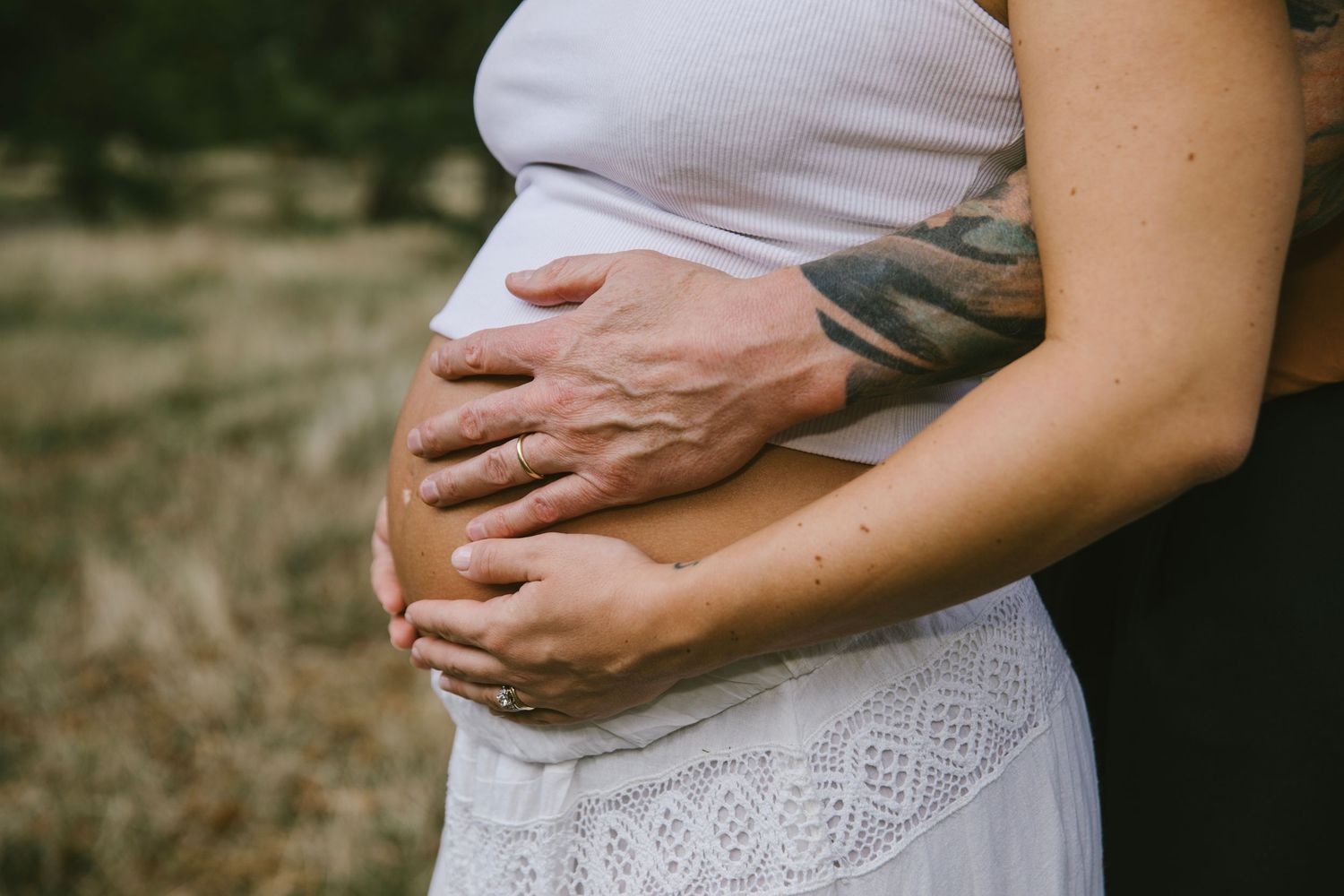 An intimate black and white maternity portrait of a couple in white shirts against dark background, in Stoke Newington, London.