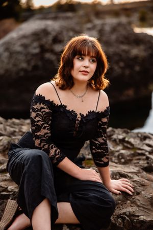 Portrait on rocky outcrop wearing black lace dress at sunset.