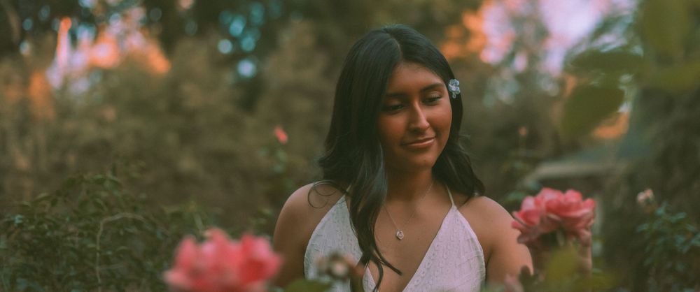 sweet 16 portrait photography in a garden with blooming pink flowers and a dreamy cinematic atmosphere