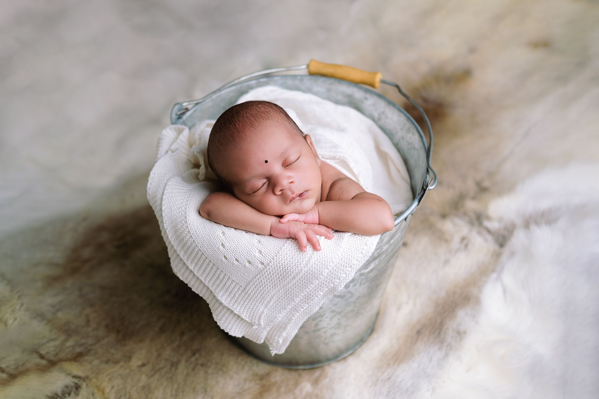 Sleeping newborn boy curled up in bucket, with reindeer fleece, Abigail Smith Photography