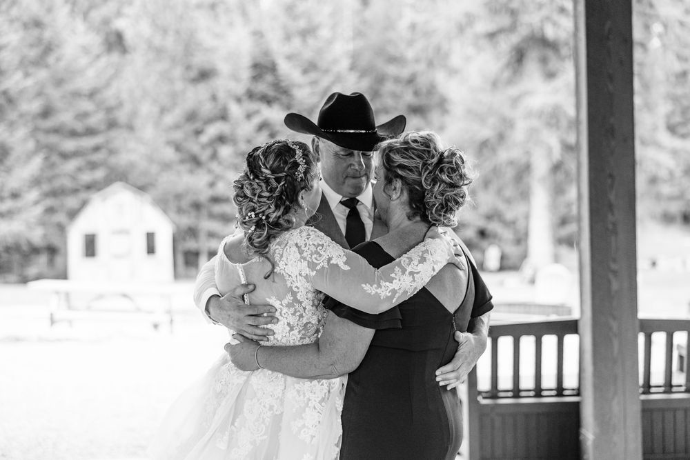 A black and white wedding photograph showing a dance moment on a porch with a rustic building in the background.