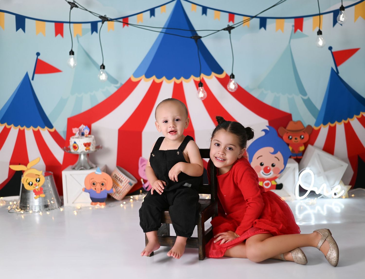 A series of four baby photos in a circus-themed setting with red, white and blue decorations and festive lighting.