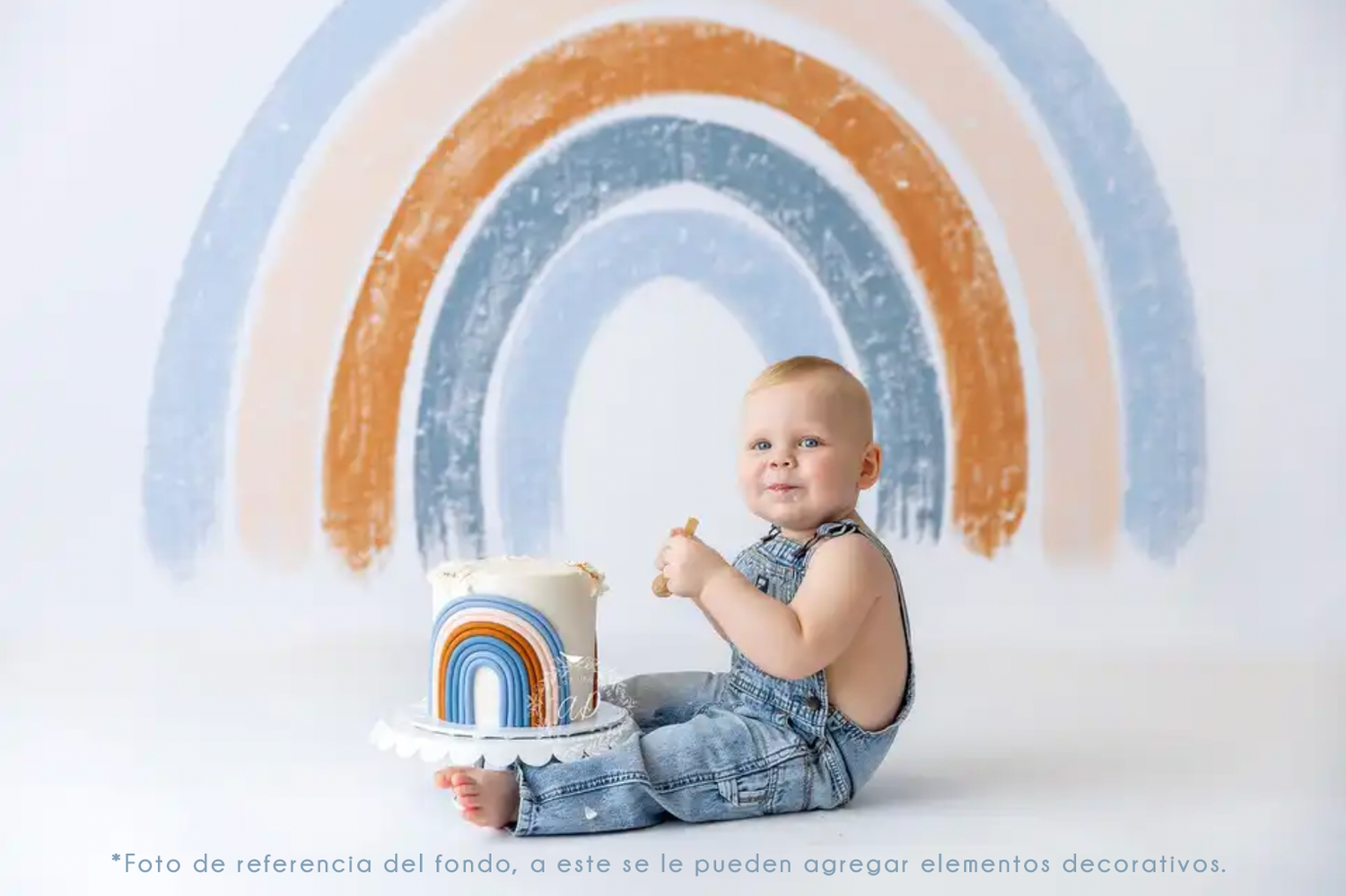 A baby in overalls sits against a painted pastel rainbow backdrop while holding a wooden number one.
