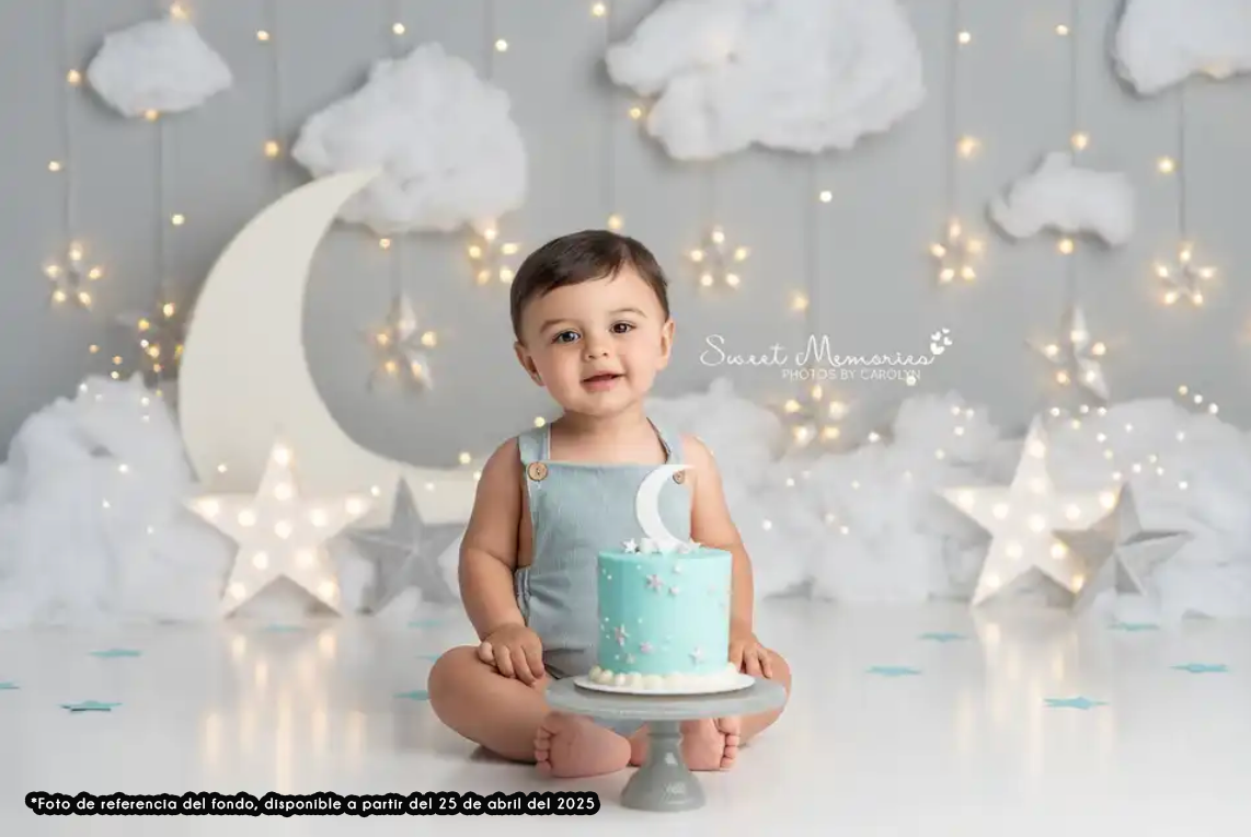 A cake smash photo setup with clouds, stars and moon decorations on a gray backdrop.