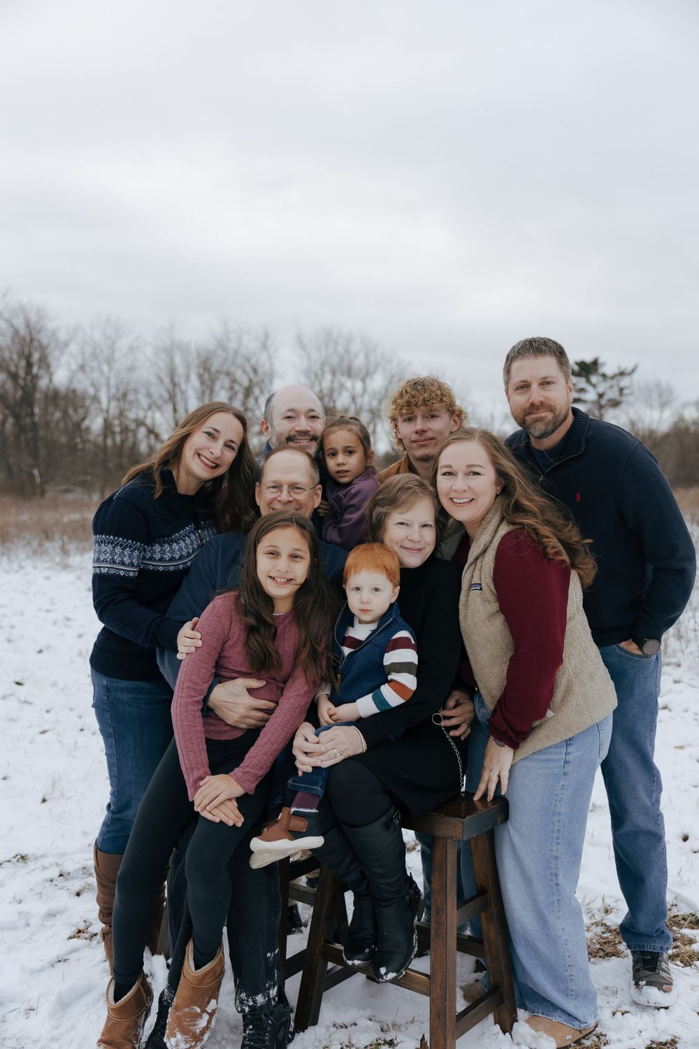 A group poses together on a snowy winter day wearing casual sweaters and warm clothing.