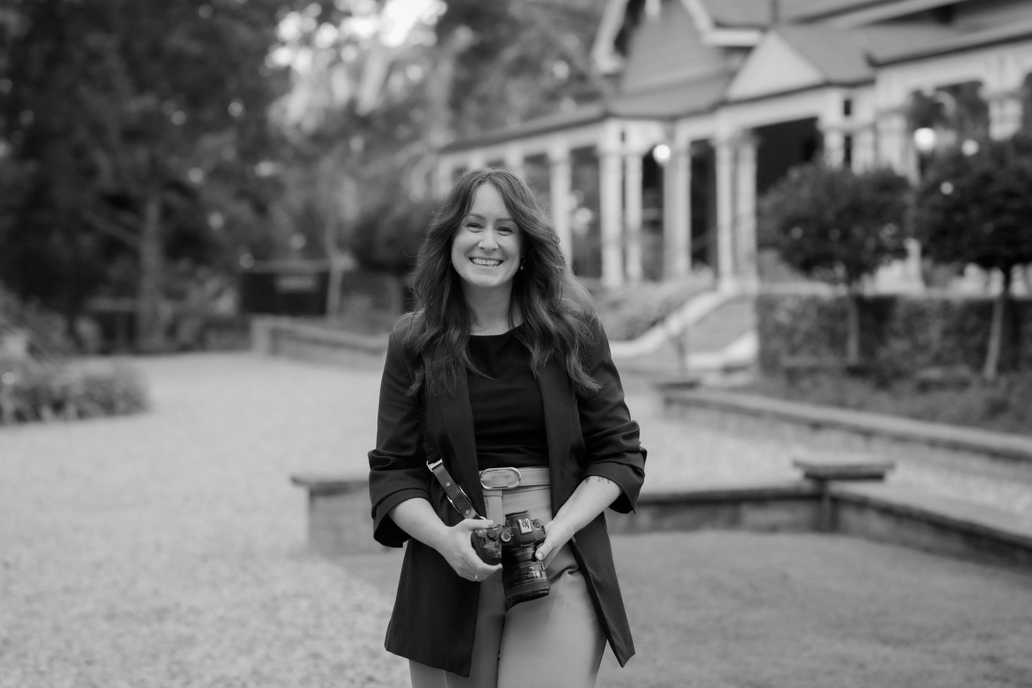 Black and white portrait in orchard with border collie dog laying in grass.