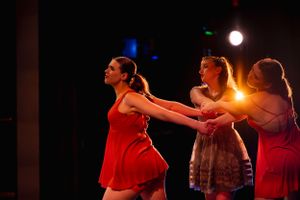 Dance ensemble performs coordinated movements under warm stage lights.