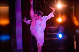 Modern dancer performs dramatic pose under stage lighting.