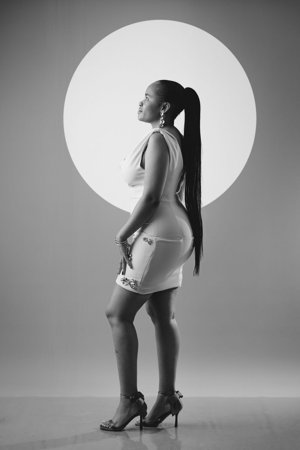 A black and white photo series showing progressive close-up shots of legs in high heels against a white backdrop.