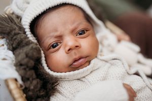 newborn in ivory sweater with eyes open.