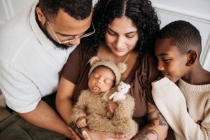 family surrounding newborn baby in a brown bear outfit