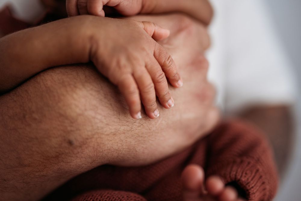 close up of newborn hand resting on fathers hand