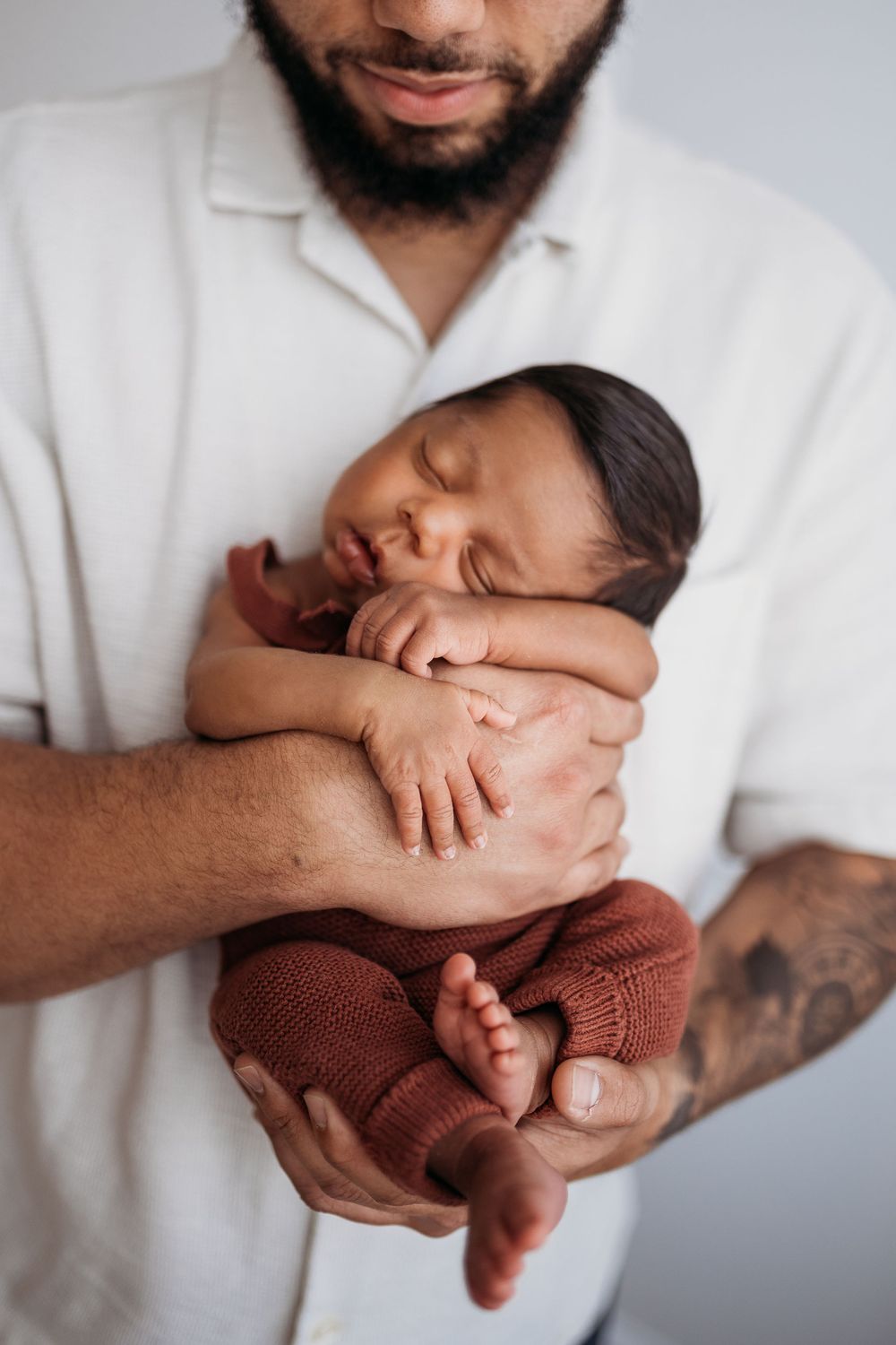 father holding newborn in his hands resting against his chest.