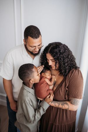 family embracing newborn next to a window.