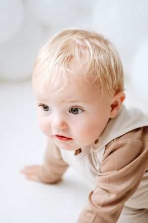 Blurry artistic photo series showing multiple profile views of a young child in a beige sweater against a light background.