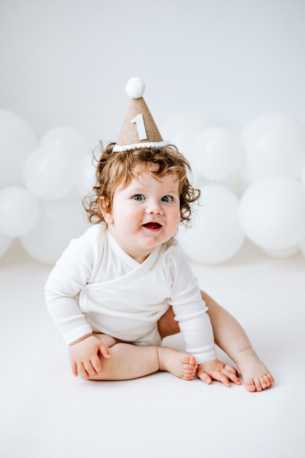 first birthday photoshoot in Nottinghamshire with white balloons and hessian party hat