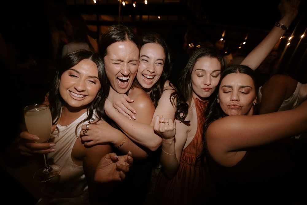 A group of friends having fun and laughing together at a dimly lit party or social gathering.