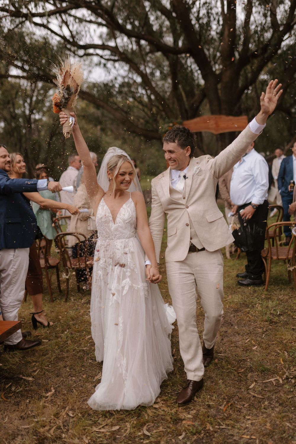 Wedding celebration with joyful dancing and raised arms in a rustic outdoor setting.