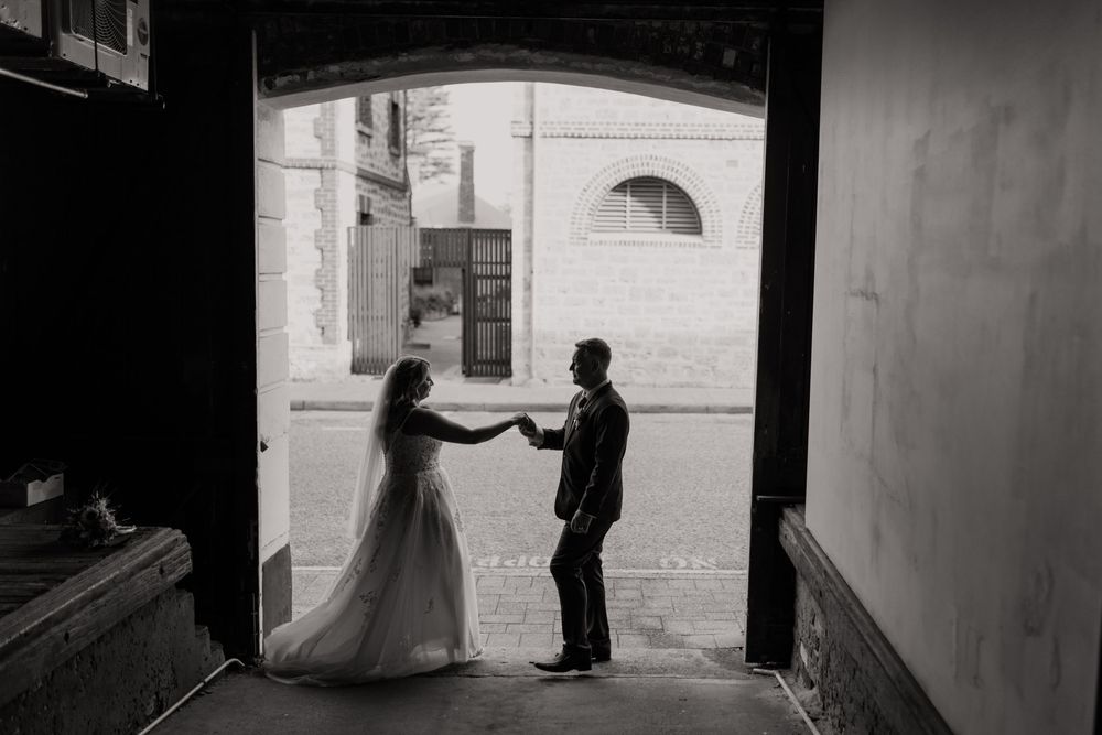 A black and white series of candid wedding moments showing silhouettes and movement in a venue hallway.