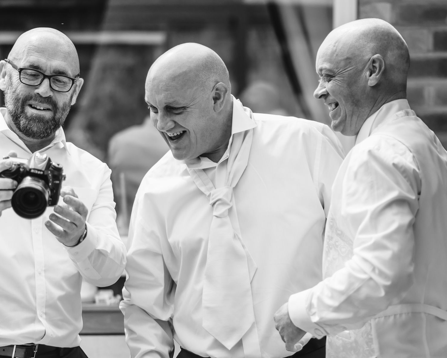 A series of black and white photos shows a group of people in white shirts sharing laughs and smiling moments together.