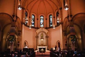 Panoramic view of a church interior with warm lighting and arched architecture featuring stained glass windows.