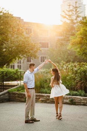 Couple dances in golden sunset light outside stone building.