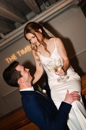 A couple shares an intimate moment on their wedding day as they dance together, with 'THE TIME' illuminated on the wall.