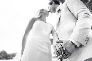 Black and white portrait of newlyweds holding hands in elegant attire.