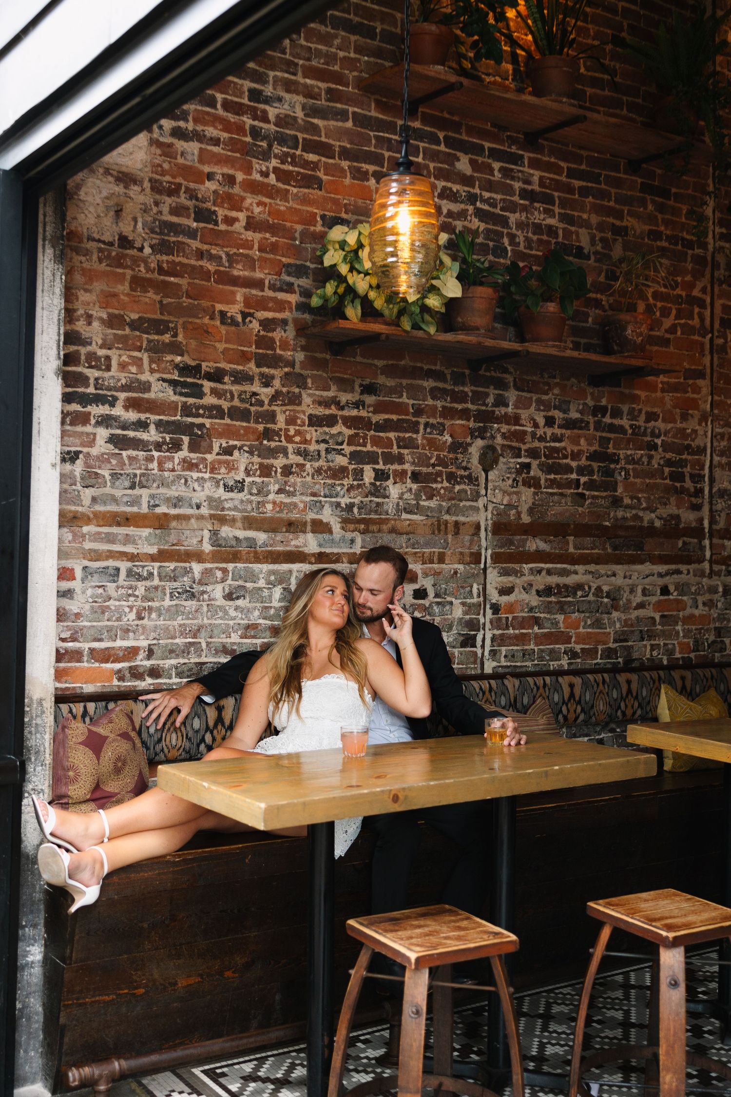 An intimate wedding reception moment in a rustic brick-walled venue with industrial lighting.