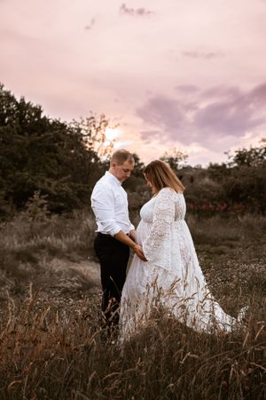 A romantic sunset engagement session in a golden field with couple embracing in formal attire.