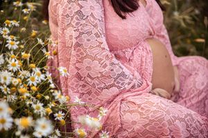 A feminine lace pink dress against a backdrop of blooming white daisies in a garden setting.