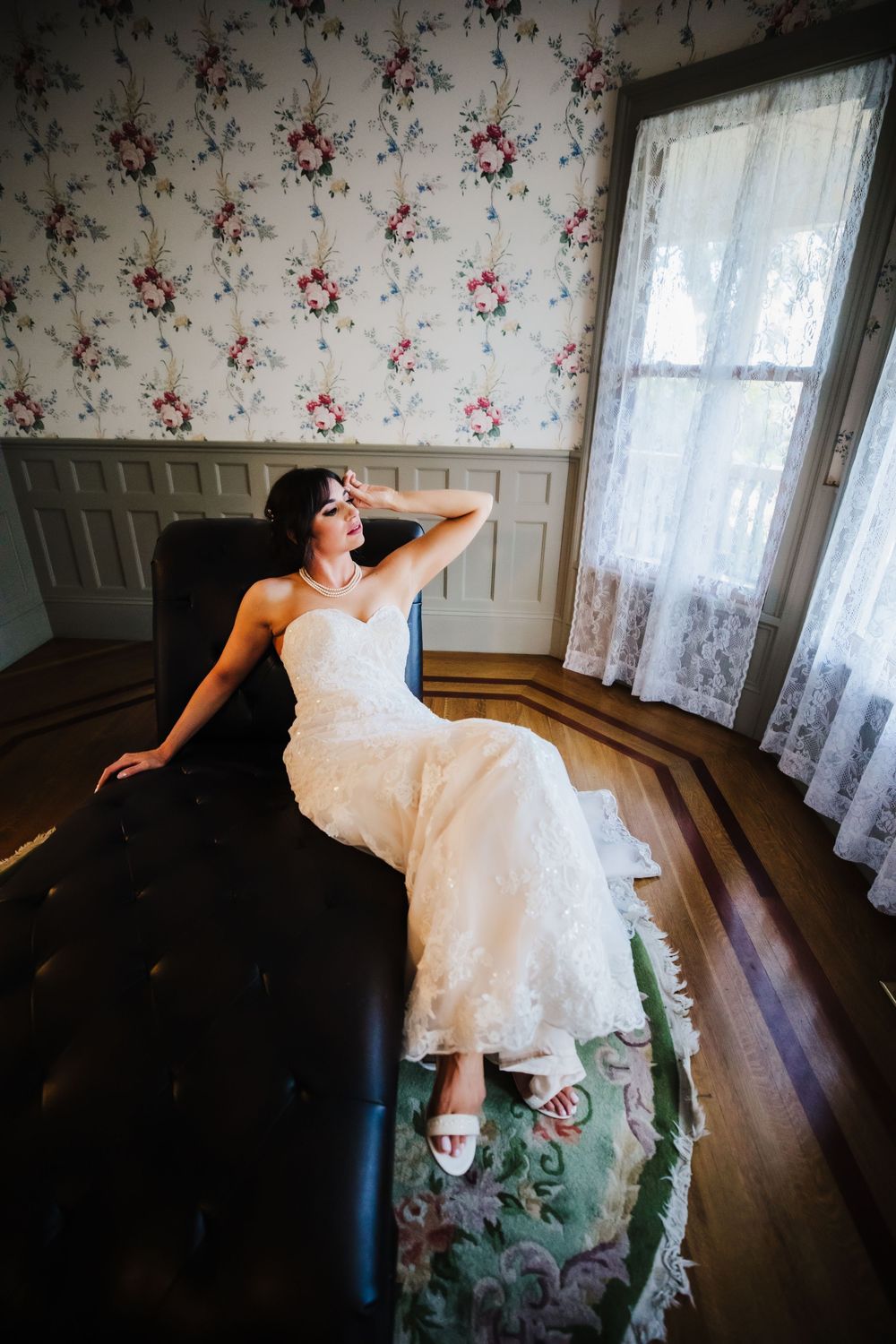 Bride in wedding gown poses on a lounge chair in front of bay windows Dickson, TN