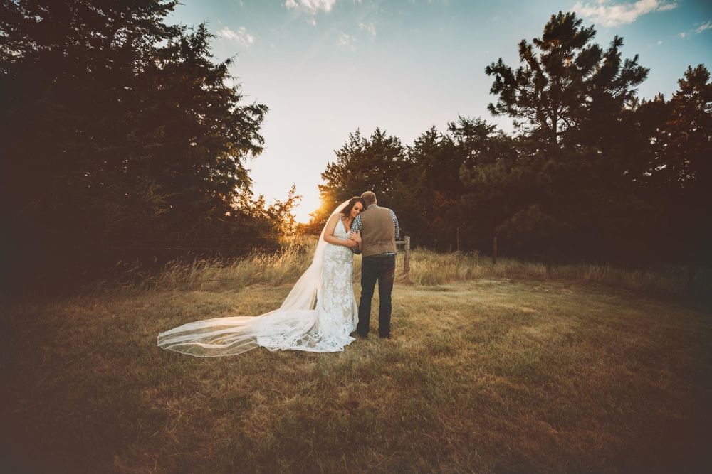 Bride and groom standing in field surrounded by trees at sunset in Dickson, TN